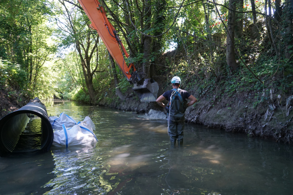 Grue prélevant des sédiments dans le Cubry pour stabiliser le tube PEHD DN800 et étancher l’entrée amont